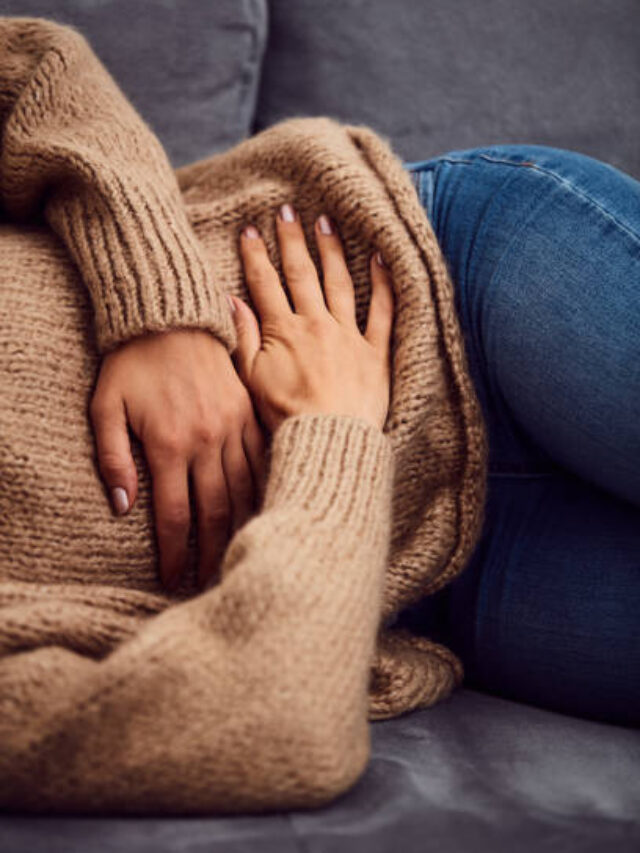 Woman having stomach issues / problems while lying on the couch.