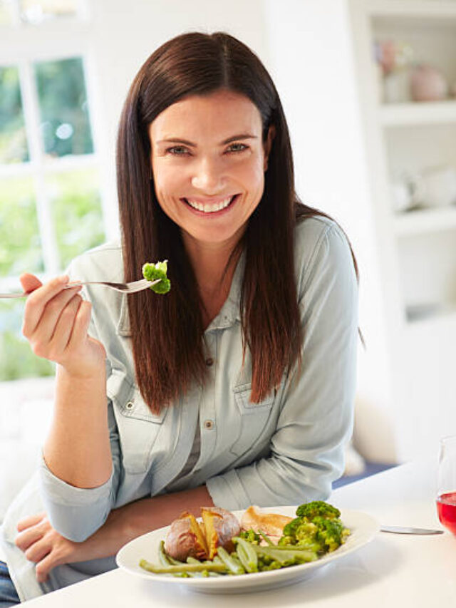 Portrait Of Woman Eating Healthy Meal In Kitchen Smiling To Camera